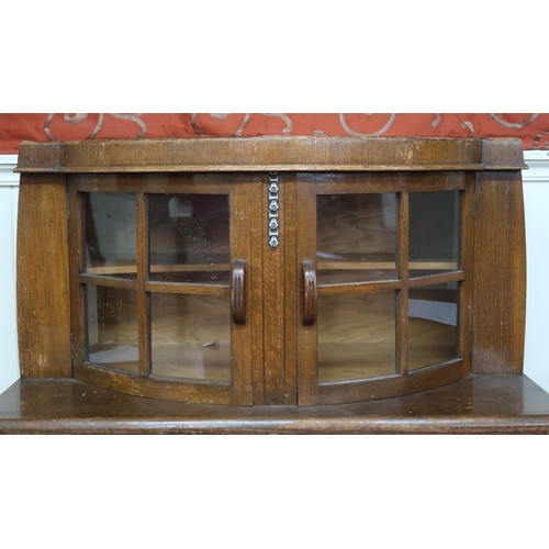 14 - An early 20th century oak Art Deco sideboard with pair of bow fronted glazed doors over two short dr... 