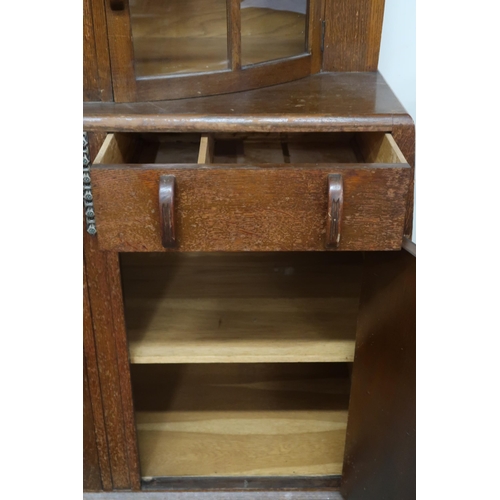 14 - An early 20th century oak Art Deco sideboard with pair of bow fronted glazed doors over two short dr... 