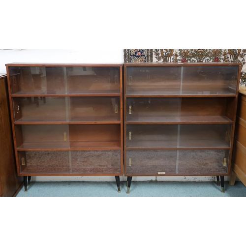 18 - A pair of mid 20th century stained teak bookcases with glass sliding doors on ebonised supports,112c... 