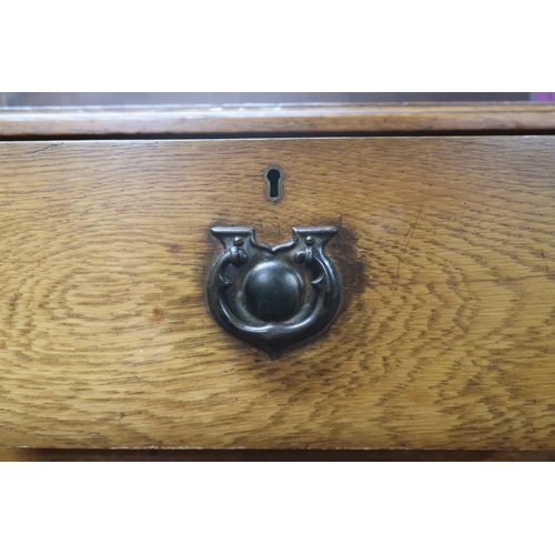 25 - A 20th century oak two over three chest of drawers with stylized drawer pulls, 98cm high x 99cm wide... 