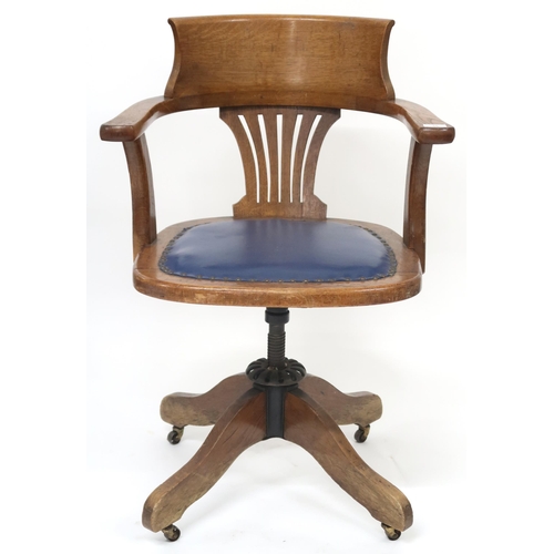 30 - An early 20th century oak swivel desk chair with hoop back over blue upholstered seat on revolving q... 