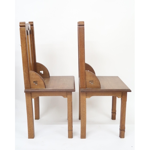 32 - A pair of early 20th century oak ecclesiastical style chairs with pierced trefoil decorations on squ... 