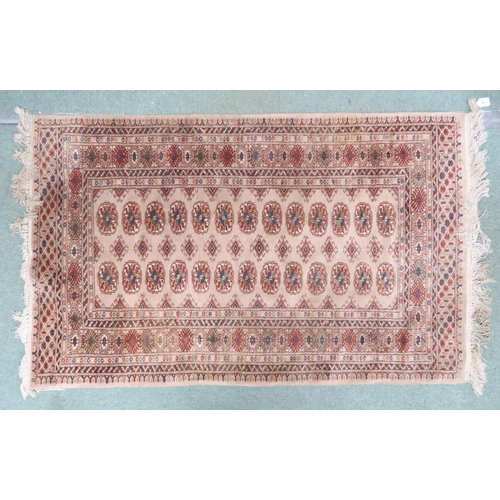 43 - A beige ground Pakistani Bokhara rug with lozenge patterned ground within multicoloured geometric bo... 