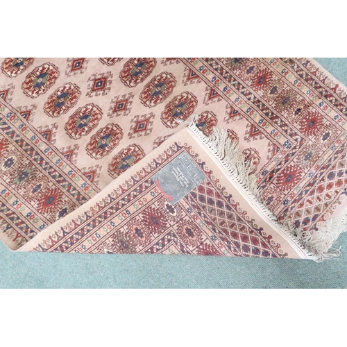 43 - A beige ground Pakistani Bokhara rug with lozenge patterned ground within multicoloured geometric bo... 