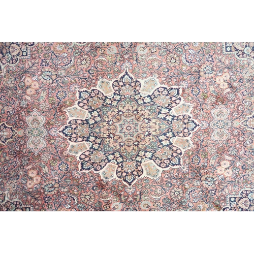 47 - A pink ground Tabriz rug with dark blue sunburst central medallion and matching spandrels on a flora... 