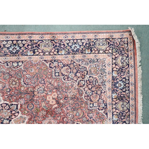 47 - A pink ground Tabriz rug with dark blue sunburst central medallion and matching spandrels on a flora... 