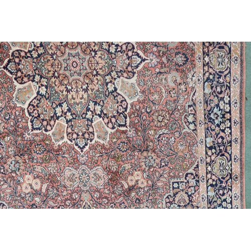 47 - A pink ground Tabriz rug with dark blue sunburst central medallion and matching spandrels on a flora... 