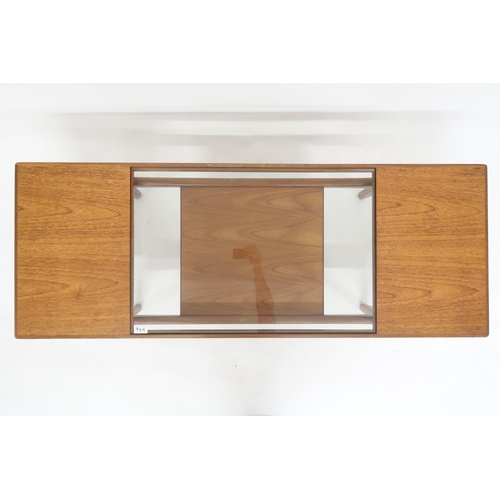 94A - A mid 20th century G Plan teak glass topped coffee table with shaped supports joined by lower tier, ... 