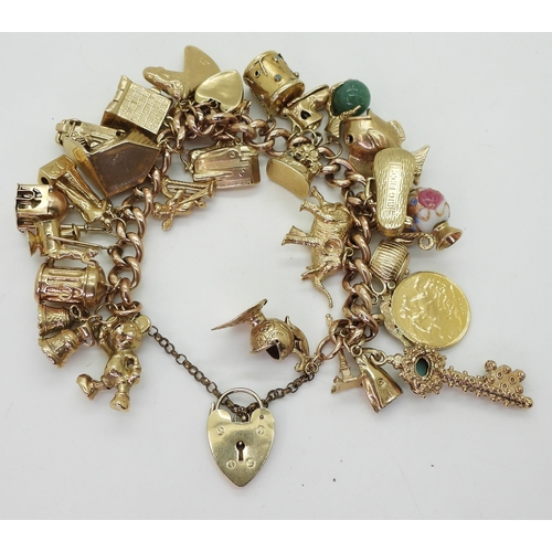 700 - A 9ct gold extensive charm bracelet, with twenty-nine attached charms to include a 1912 gold full so... 