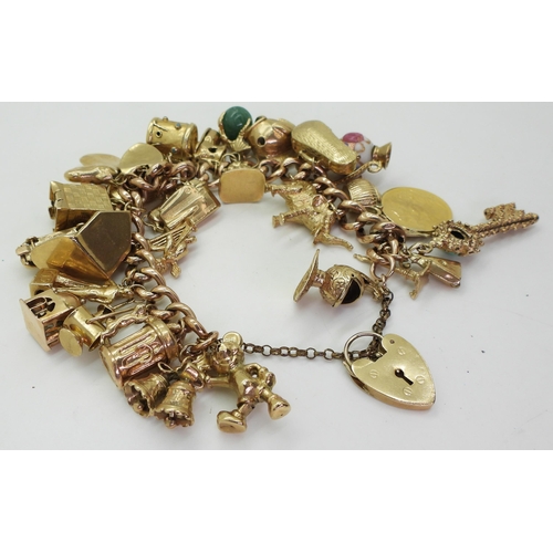 700 - A 9ct gold extensive charm bracelet, with twenty-nine attached charms to include a 1912 gold full so... 