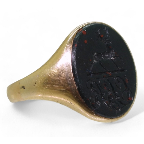 802 - A yellow metal signet ring set with a large bloodstone intaglio carved with a stag and a monogram, s... 