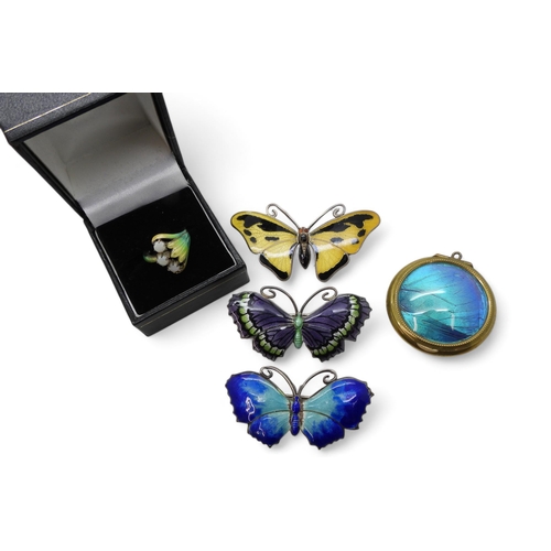 911 - Three butterfly brooches, two in silver and the yellow example in white metal, a silver cold enamel ... 