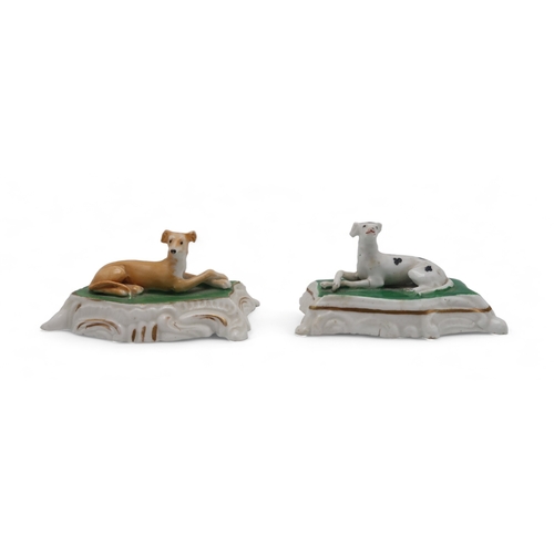 2329 - TWO PORCELAIN MODELS OF GREYHOUNDS OR WHIPPETSprobably Staffordshire, each modelled sitting on a cus... 