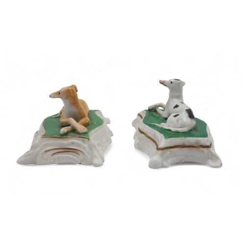 2329 - TWO PORCELAIN MODELS OF GREYHOUNDS OR WHIPPETSprobably Staffordshire, each modelled sitting on a cus... 