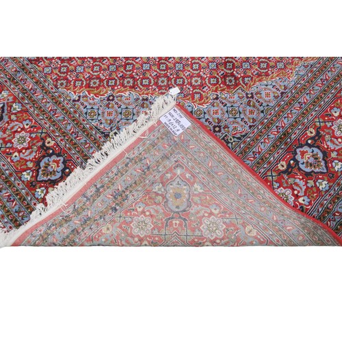 2138 - A RED GROUND TRADITIONAL BIJAR CARPET with dark and light blue central medallion and matching spandr... 