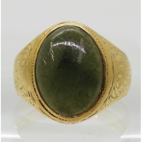 723 - A bright yellow metal signet ring, stamped 90% set with a green hardstone, with engraved shoulders, ... 