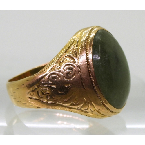 723 - A bright yellow metal signet ring, stamped 90% set with a green hardstone, with engraved shoulders, ... 