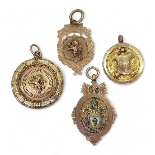 838 - Two 9ct gold enamelled detail medallions, a 9ct round medallion with shield and a yellow metal lion ... 