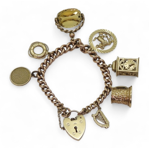 843 - A 9ct gold tapered curb link charm bracelet with a heart shaped clasp and seven attached 9ct gold ch... 