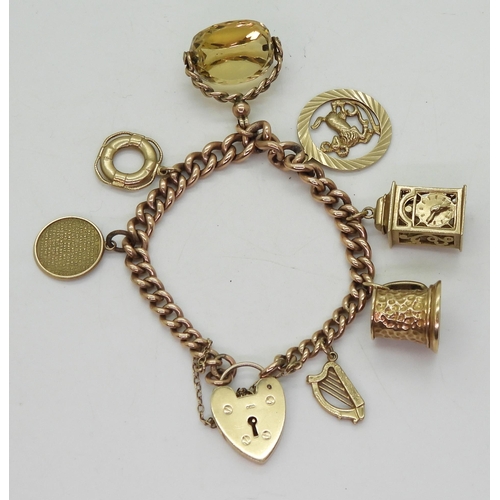 843 - A 9ct gold tapered curb link charm bracelet with a heart shaped clasp and seven attached 9ct gold ch... 