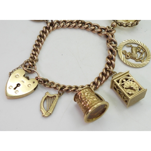 843 - A 9ct gold tapered curb link charm bracelet with a heart shaped clasp and seven attached 9ct gold ch... 