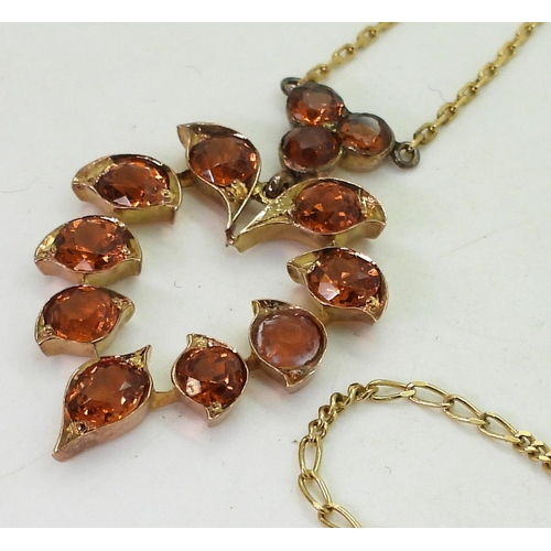 855 - A pendant necklace set with bright orange gemstones, mounted in yellow metal with a yellow metal cha... 