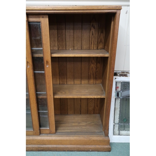 125 - A large early 20th century oak Arts & Crafts bookcase with three leaded glass sliding doors on p... 