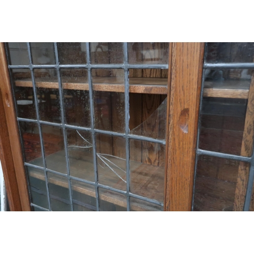 125 - A large early 20th century oak Arts & Crafts bookcase with three leaded glass sliding doors on p... 