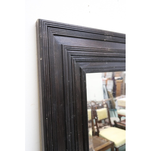 128 - A large stained oak bevelled glass wall mirror, 151cm x 150