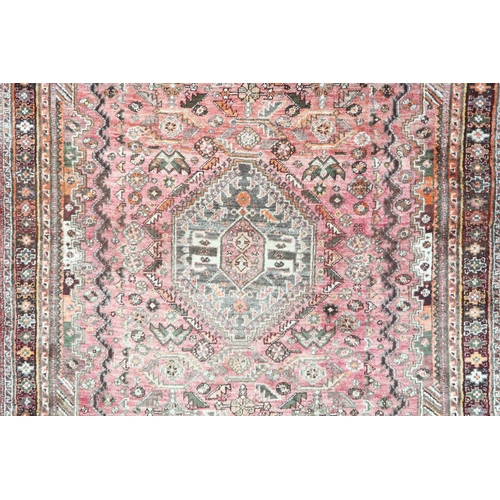 18 - A pink ground Persian Qashqai rug with dark geometric central medallion and matching spandrels on ge... 