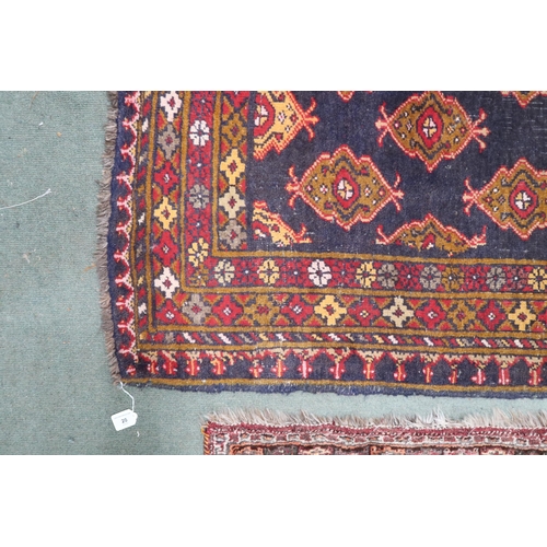 20 - A dark blue ground Iranian Turkman rug with all over lozenge patterned ground within multicoloured g... 