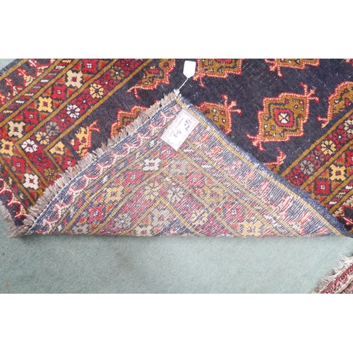 20 - A dark blue ground Iranian Turkman rug with all over lozenge patterned ground within multicoloured g... 