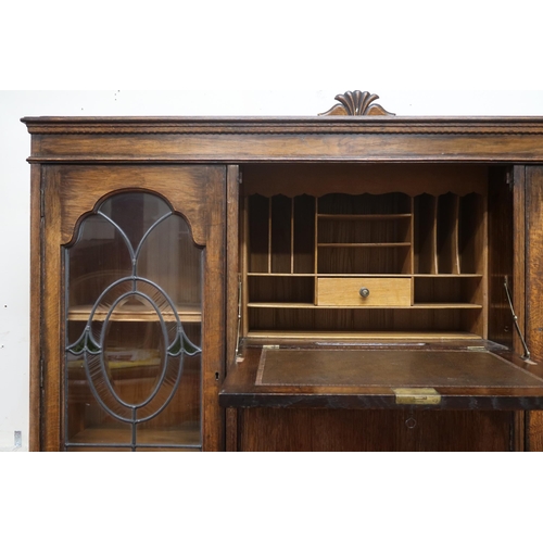 6 - An early 20th century oak bureau bookcase with central panel fall front writing compartment over sin... 