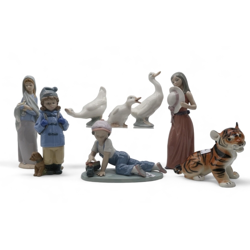 173 - A collection of Lladro and Nao figures of children and geese and a unmarked Lomonosov lion