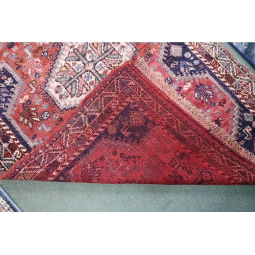 107 - A red ground Hamadan rug with multicoloured medallions and dark blue spandrels on geometric floral g... 