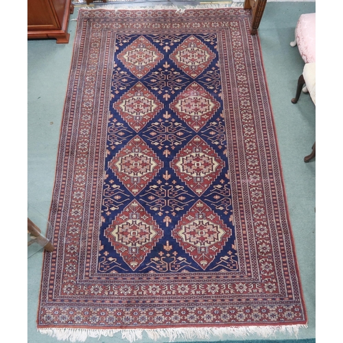 112 - A blue ground Persian style rug with cream and terracotta lozenges within multicoloured geometric bo... 