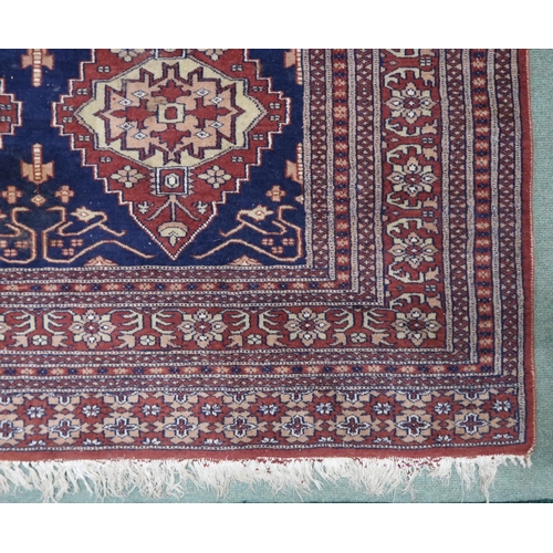 112 - A blue ground Persian style rug with cream and terracotta lozenges within multicoloured geometric bo... 