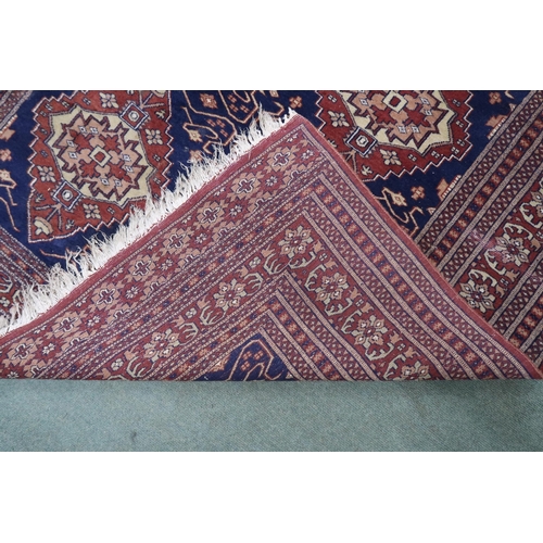 112 - A blue ground Persian style rug with cream and terracotta lozenges within multicoloured geometric bo... 