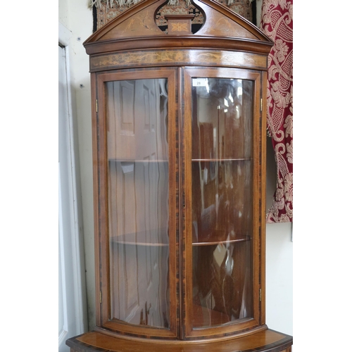 28 - A 20th century mahogany and fruitwood inlaid Regency style bow front corner cabinet with pair of gla... 