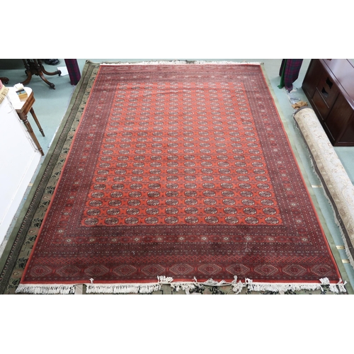 52 - A large red ground Pakistani Bokhara style rug with allover lozenge patterned ground within geometri... 