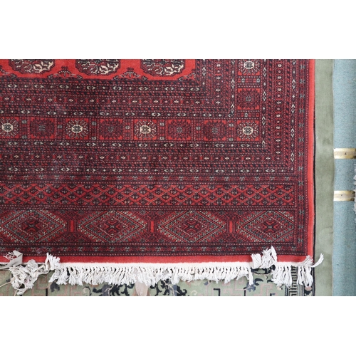 52 - A large red ground Pakistani Bokhara style rug with allover lozenge patterned ground within geometri... 