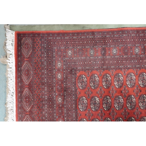 52 - A large red ground Pakistani Bokhara style rug with allover lozenge patterned ground within geometri... 