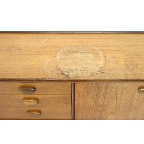 2103 - A MID 20TH CENTURY TEAK PORTWOOD SIDEBOARD with three drawers flanked by fall front drinks compartme... 