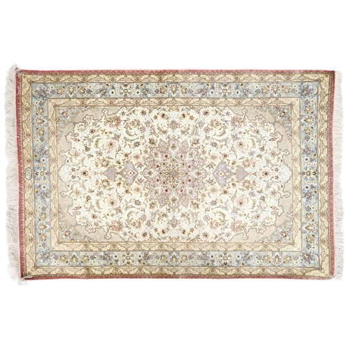 2173 - AN IVORY GROUND FINE PILE SILK SIGNED QUM RUGwith blue and beige sunburst central medallion and matc... 