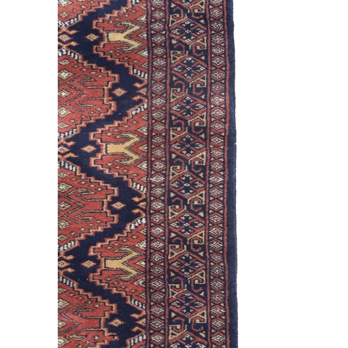 2175 - A DARK BLUE GROUND KURDISH RUNNER with all-over red geometric lozenge design within multicoloured ge... 