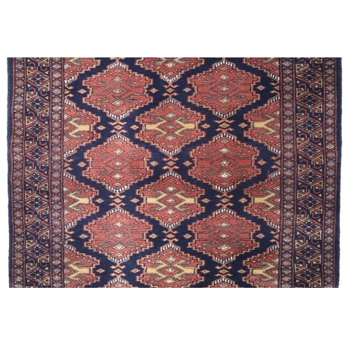 2175 - A DARK BLUE GROUND KURDISH RUNNER with all-over red geometric lozenge design within multicoloured ge... 