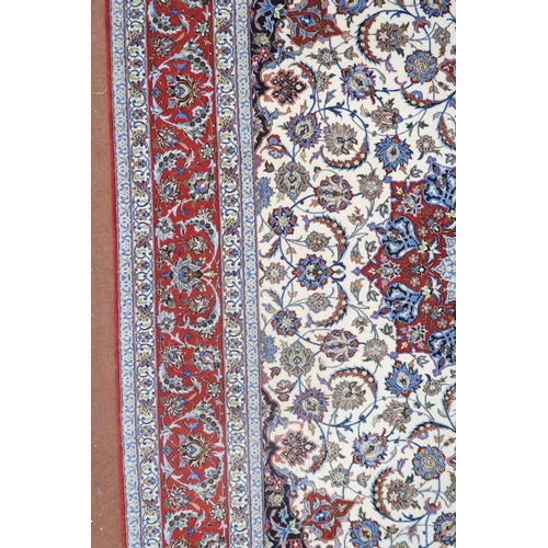 2177 - AN IVORY GROUND FULL PILE PERSIAN ISFAHAN CARPET with red central medallion and dark blue spandrels ... 