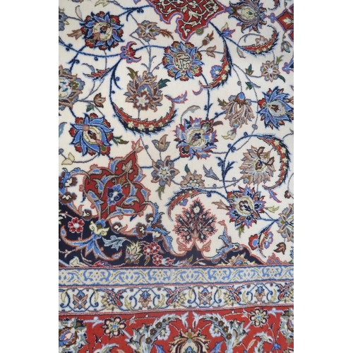 2177 - AN IVORY GROUND FULL PILE PERSIAN ISFAHAN CARPET with red central medallion and dark blue spandrels ... 