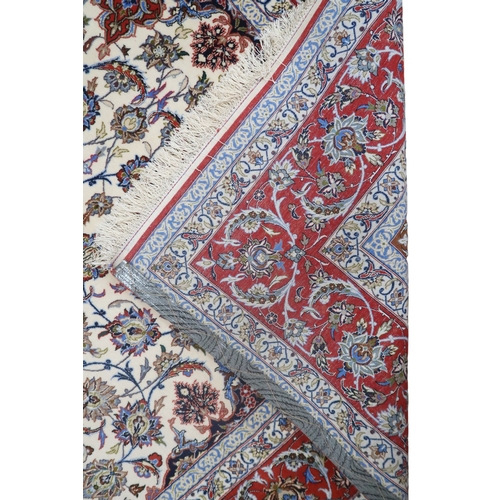 2177 - AN IVORY GROUND FULL PILE PERSIAN ISFAHAN CARPET with red central medallion and dark blue spandrels ... 