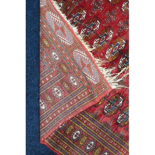 10 - A red ground fine pile Pakistani Bokara rug with all-over lozenge patterned ground within multicolou... 